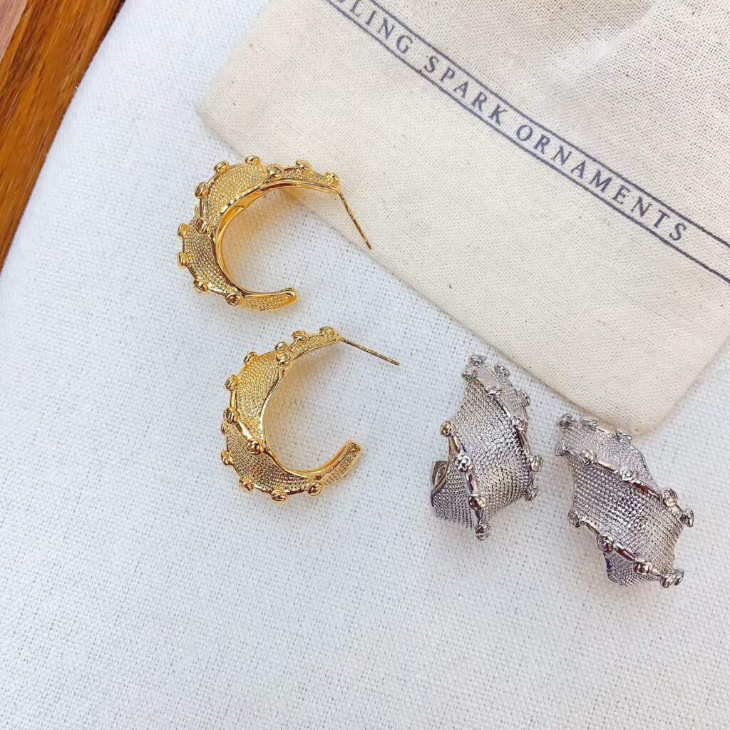 Gold and silver anti-tarnish hoop and stud earrings on linen