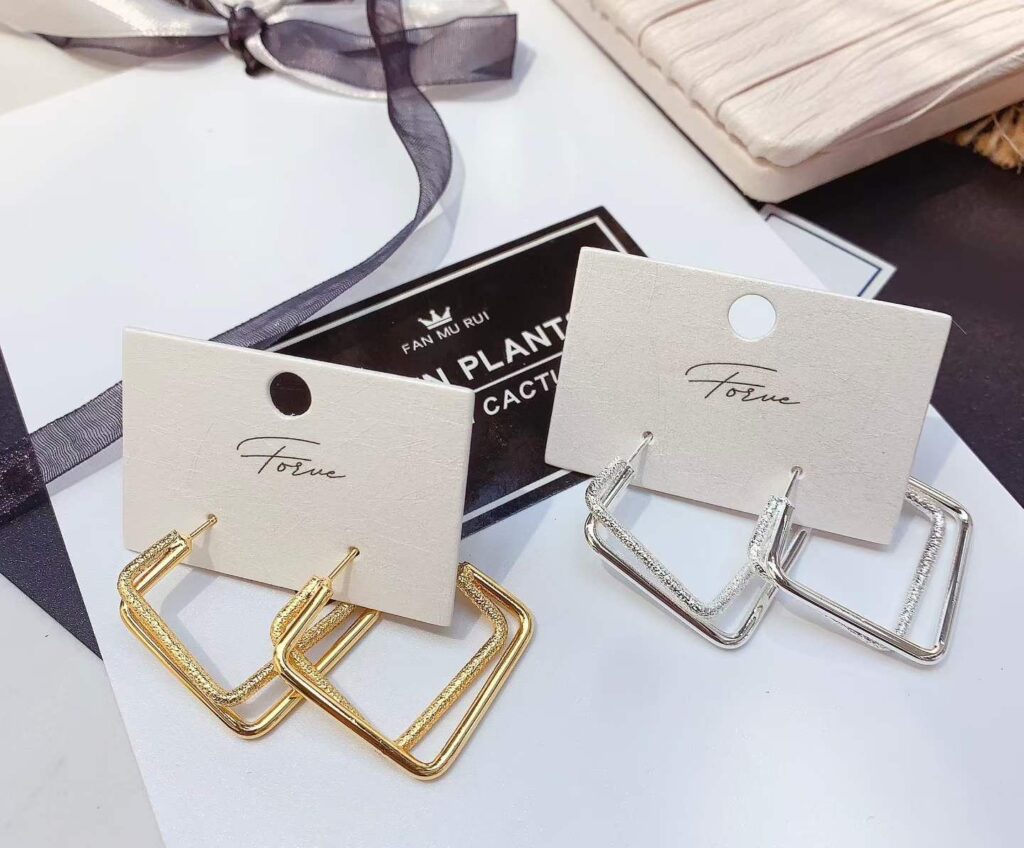 Gold and silver hoop earrings with a gift box and ribbon for Raksha Bandhan
